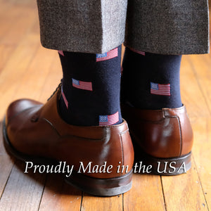 man wearing navy wool dress socks decorated with small American flags paired with brown oxfords and light grey trousers