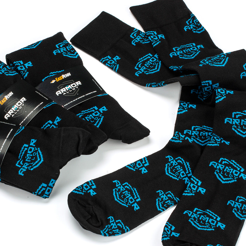 Three pairs of black over the calf dress socks socks with a bright blue 'ARMOR ALLOY' shield pattern, shown on a clean white background. Several pairs are wrapped in branded packaging with a East Penn printed.
