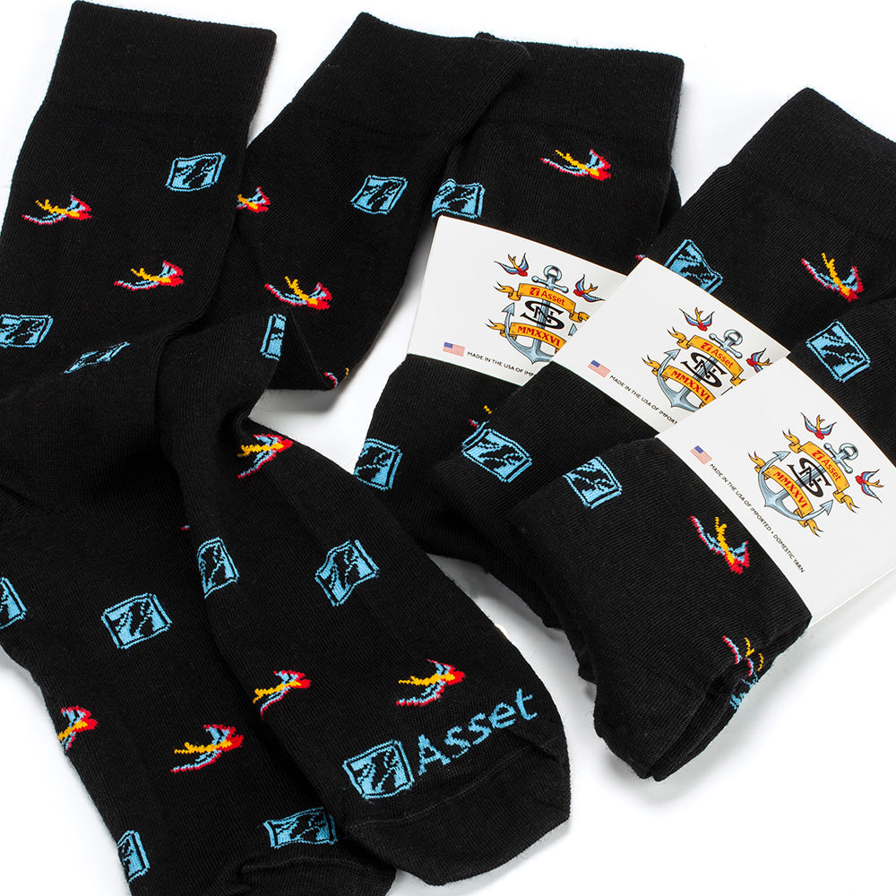 Four pairs of black dress socks with colorful marketing logos and blue 'Asset' text stitched across the toe, arranged on a white background with branded packaging.