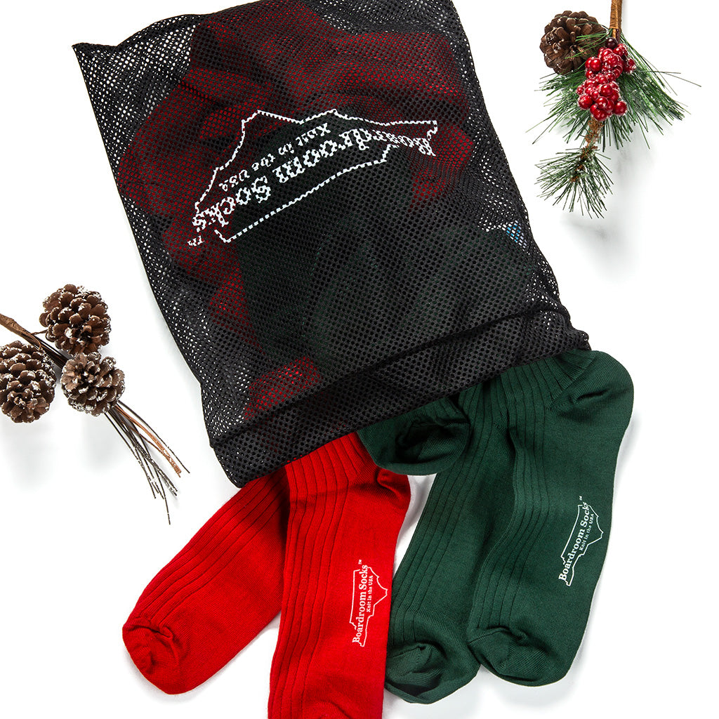 sock laundry bag filled with red and green dress socks surrounded by holiday decor