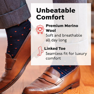 man standing wearing brown loafers, grey pants, and navy merino wool dress socks with orange dots pattern