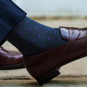 close up image of a man's foot wearing a dark brown loafer with grey cotton dress socks with a purple dot pattern