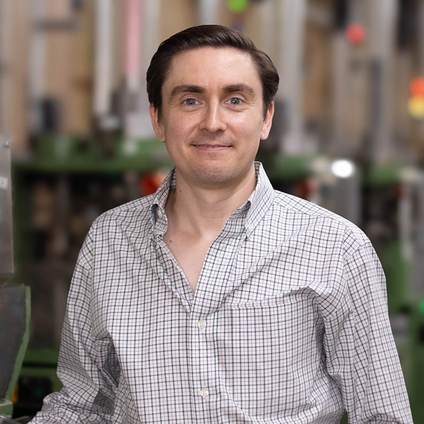 Headshot of Nathan James, CEO of Boardroom Socks, in front of knitting machines.