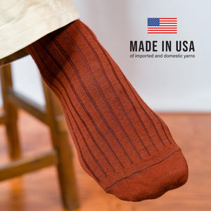 close up of a person's foot wearing Burnt Orange Merino Wool Over the Calf Dress Socks with made in usa text overlay
