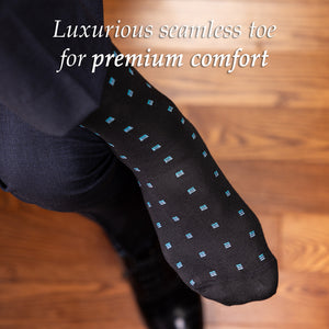 man crossing legs wearing black and blue patterned dress socks with a dark suit