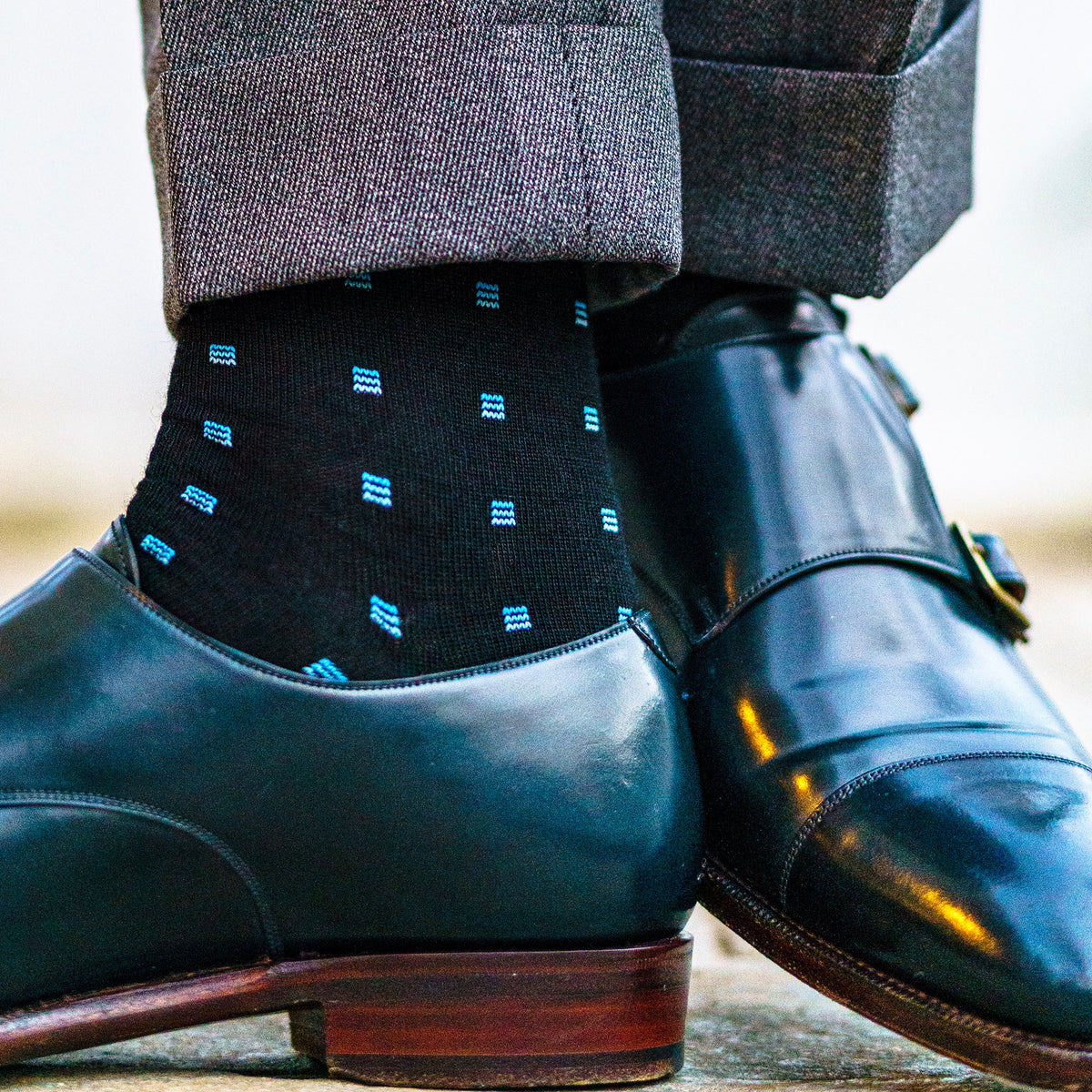 man standing with feet turned to show black and blue patterned dress socks
