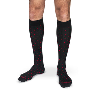 model wearing black over the calf dress socks decorated with bright red polka dots