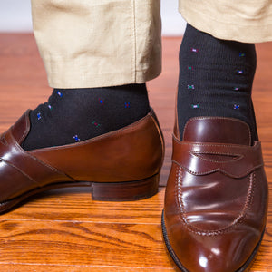 man standing on wood floors wearing brown loafers and black geometric pattern cotton over the calf dress socks
