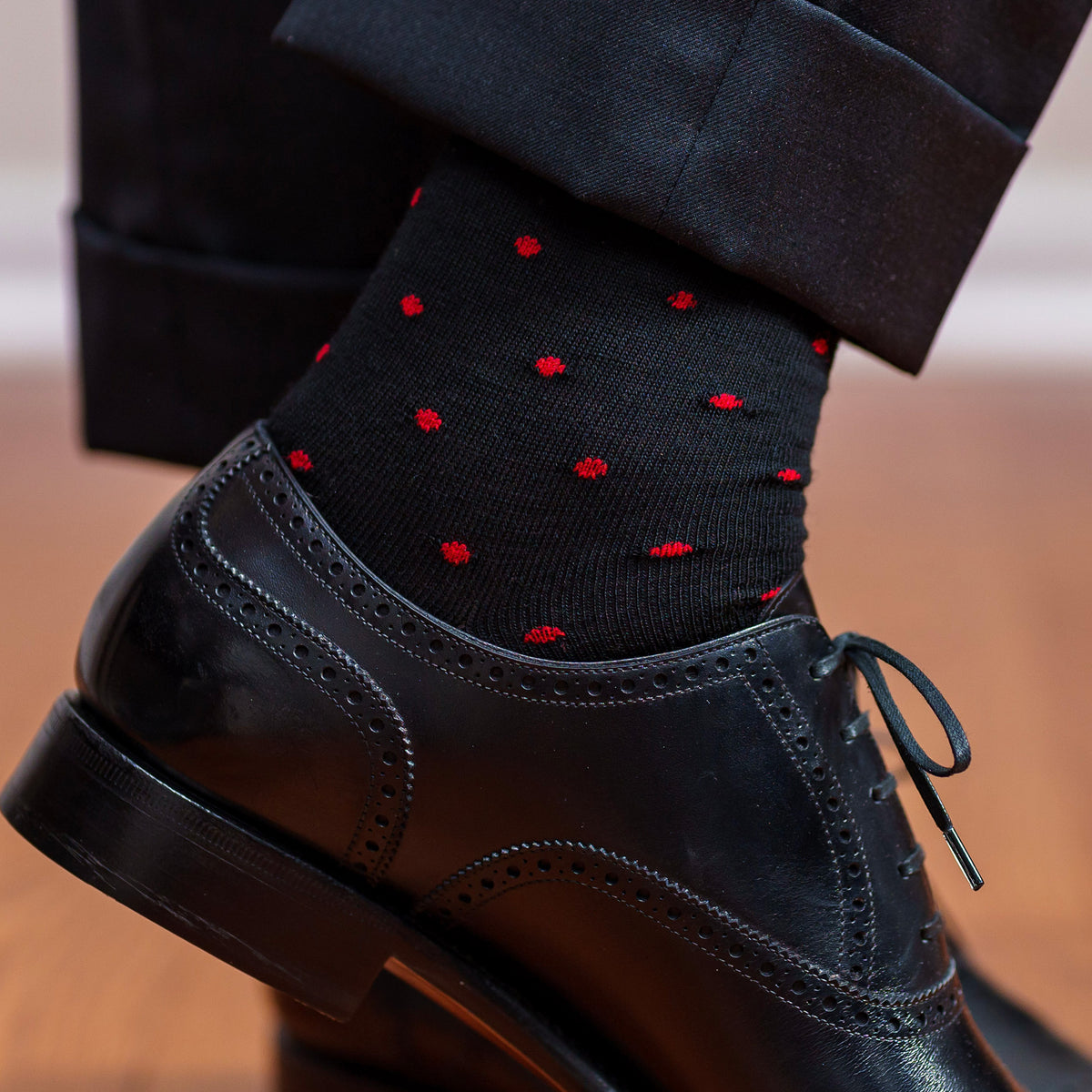 black merino wool dress socks decorated with small red polka dots worn with black oxfords and black slacks