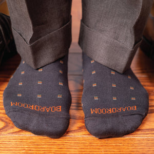 detailed image of brown patterned dress socks worn on both feet standing on wood floor