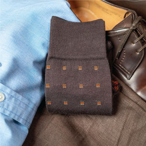 image of brown patterned dress socks laid folded flat on top of pants and shirt and loafers