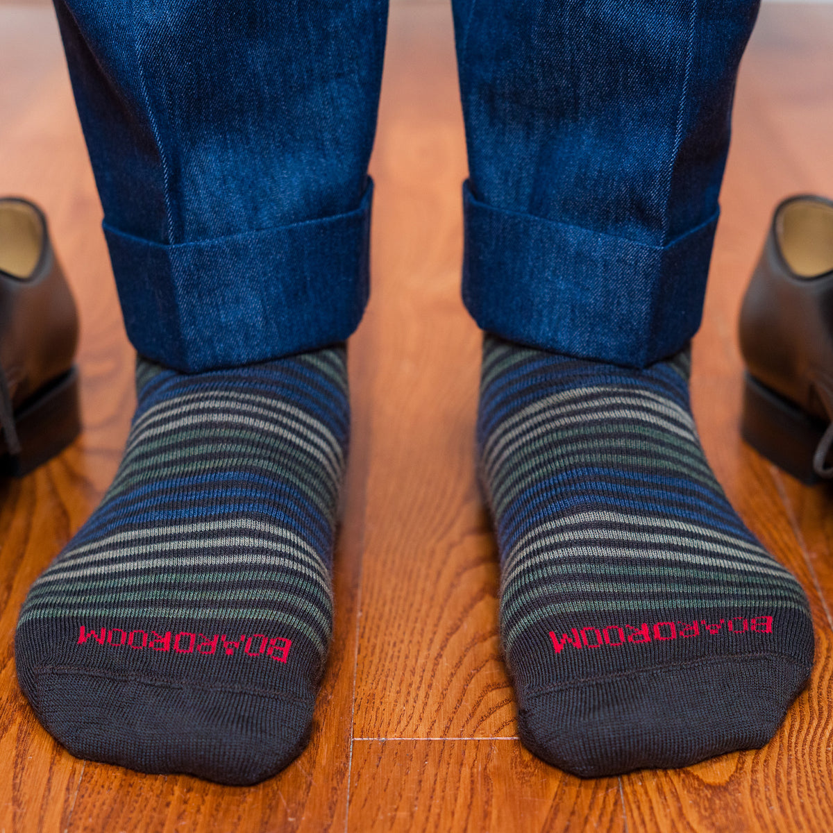 striped dress socks with &#39;BOARDROOM&#39; branding worn on a wooden floor