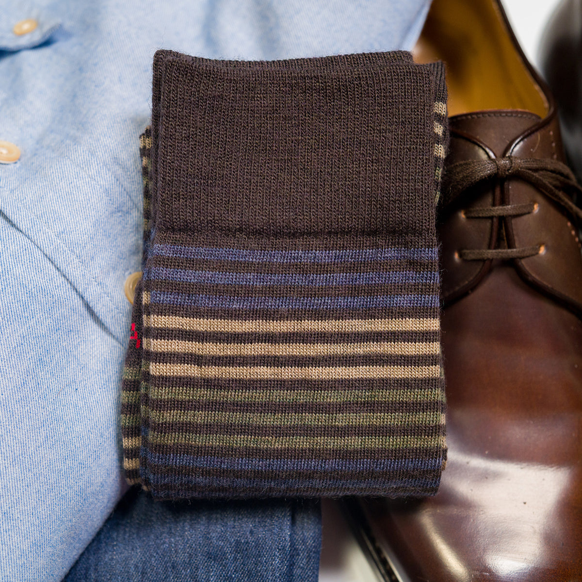 pair of brown striped dress socks atop business casual attire and brown dress shoes