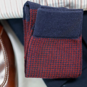 folded pair of burgundy and navy houndstooth dress socks laying on top of business casual outfit