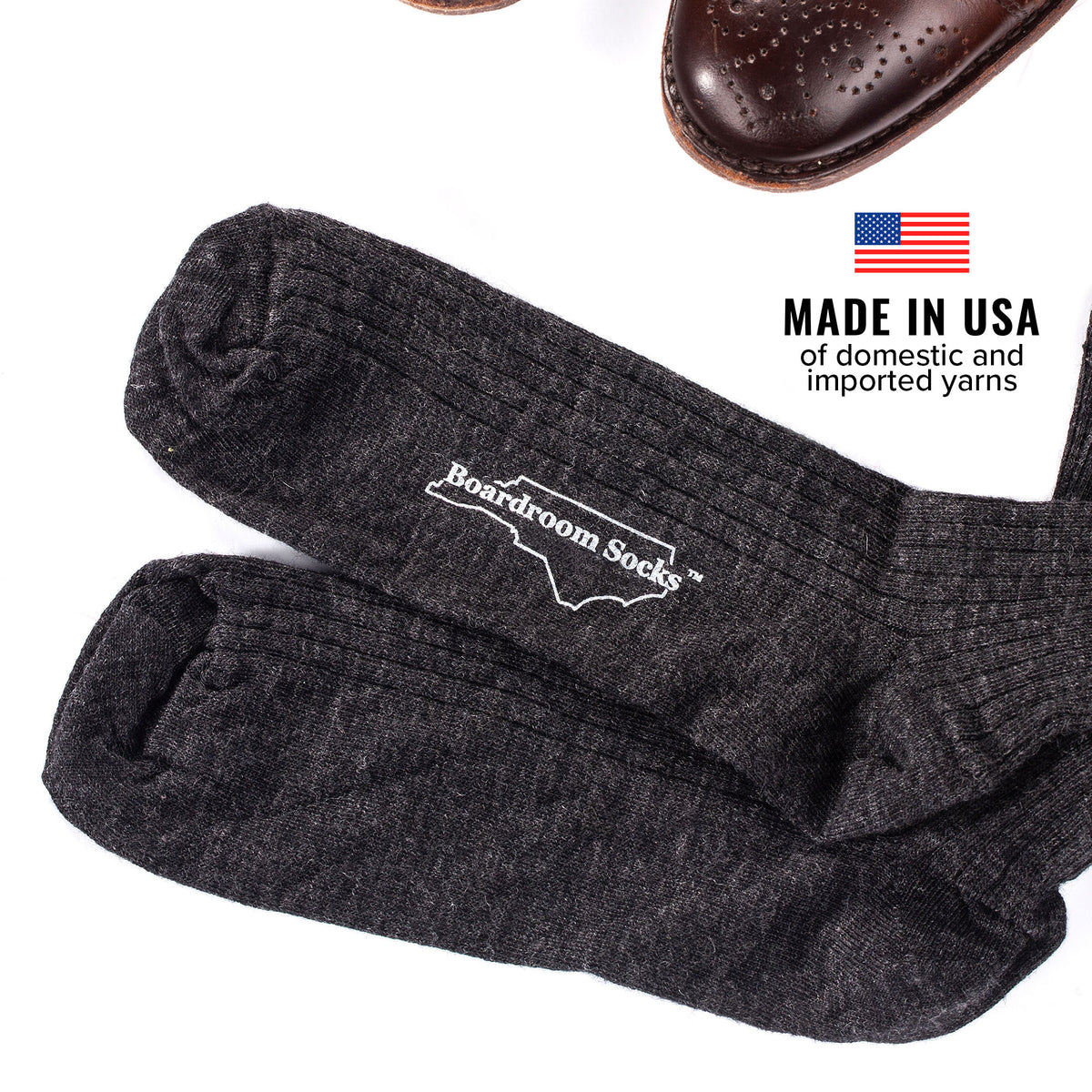 charcoal grey wool dress socks atop white table beside brown dress shoes