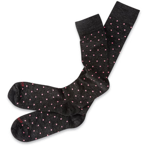 pair of over the calf charcoal grey wool dress socks decorated with pink dots laying atop white table