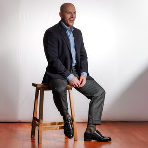 man wearing charcoal and tan shadow stripe dress socks with business casual outfit sitting on stool