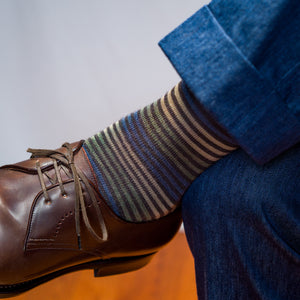 man wearing colorful brown striped dress socks with navy slacks and brown derbies while crossing is legs