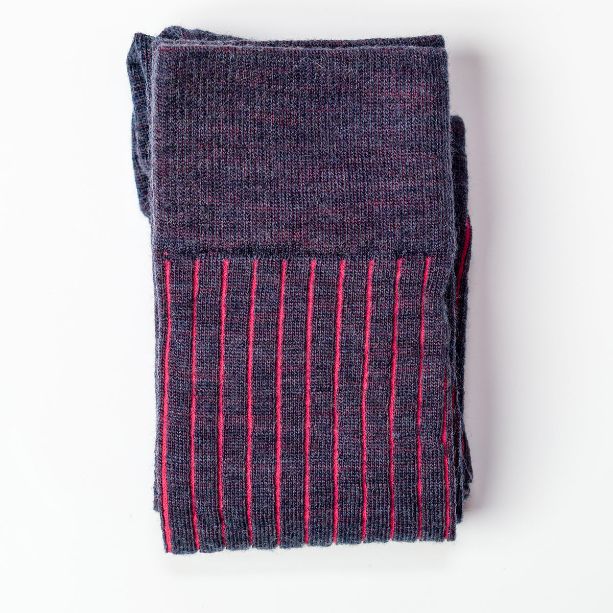 folded pair of coral and denim heather merino wool shadow stripe dress socks atop white table