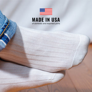 man crossing his feet wearing jeans and white merino wool dress socks and made in usa text overlay