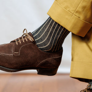 man crossing legs wearing charcoal and tan shadow stripe dress socks with tan slacks with brown suede derbies