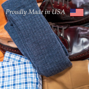 ribbed merino wool dress socks in a blue heather shade folded on top of khaki trousers and burgundy wingtips