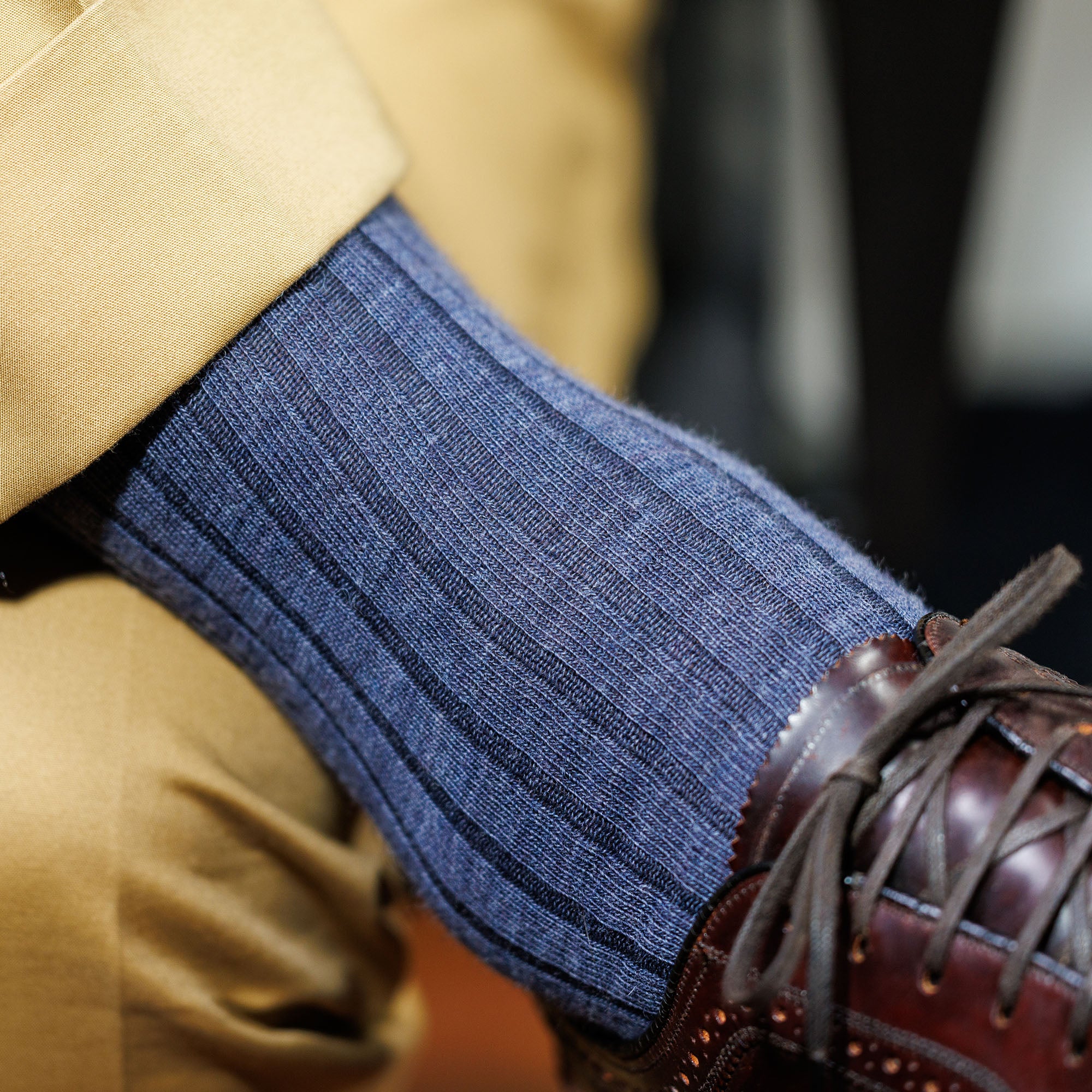 man crossing legs wearing denim heather merino wool dress socks with khaki trousers and brown dress shoes