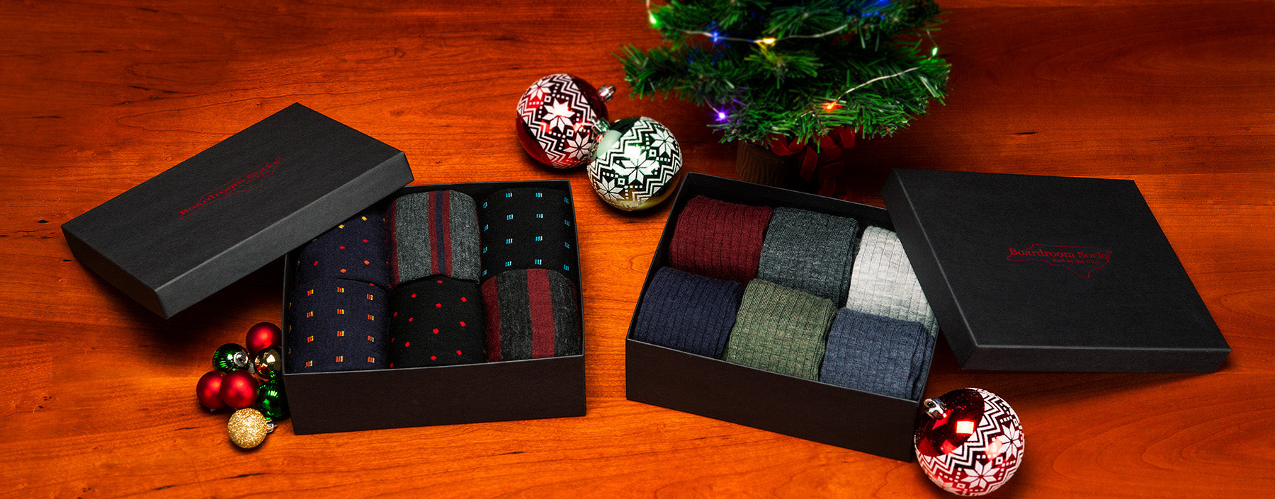 two opened gift boxes filled with dress socks and surrounded by holiday decor