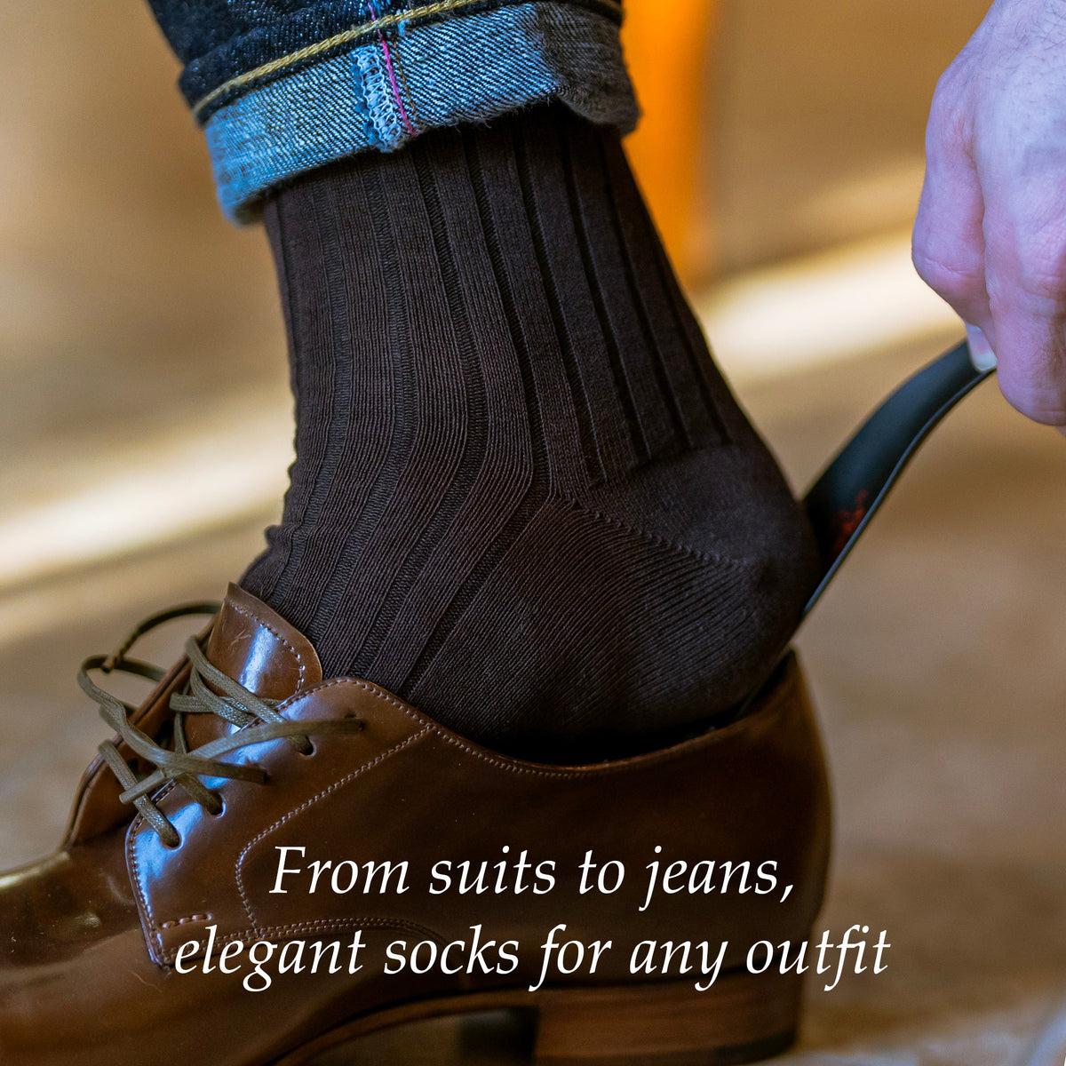 man wearing brown cotton dress socks using shoe horn to put on brown dress shoes