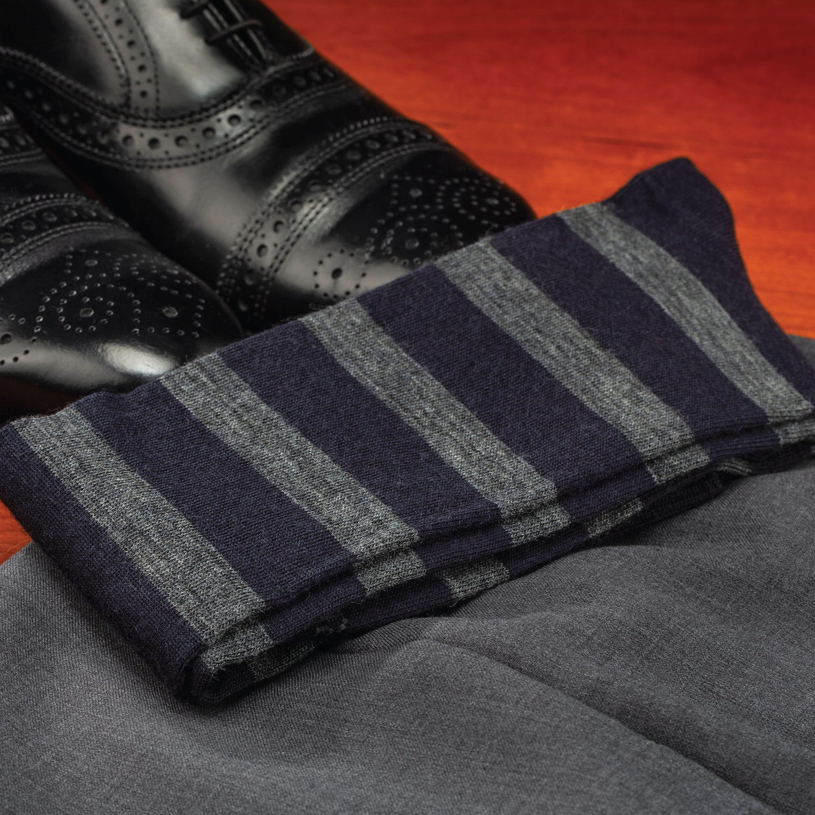 folded Grey Heather Stripes on Navy Merino Wool Over the Calf Dress Socks laying on a pair of pants and nice shoes