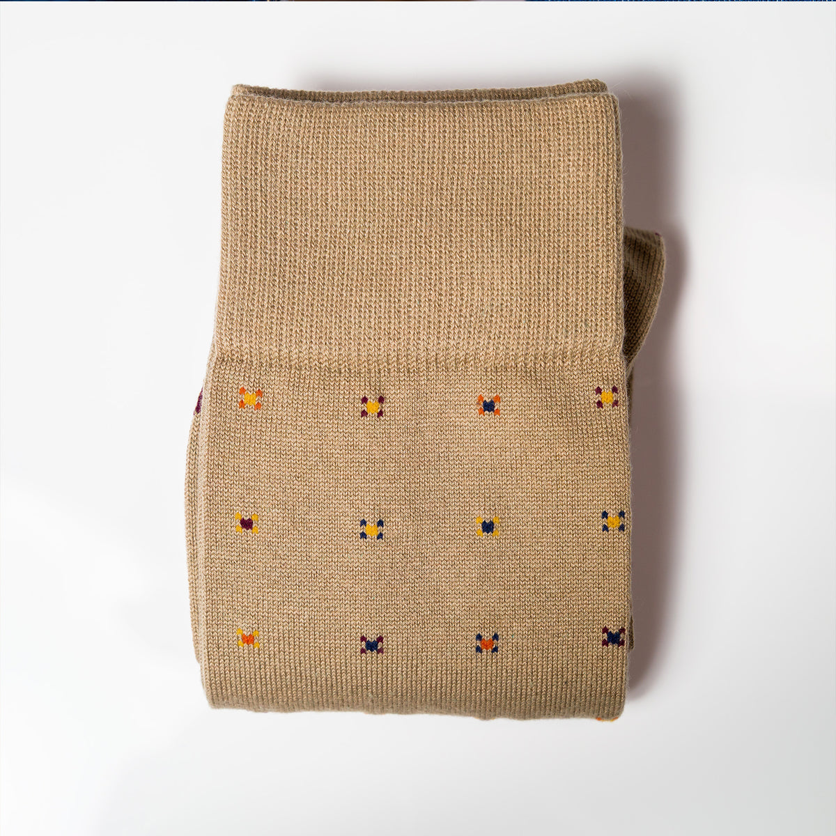 a pair of folded khaki geometric pattern dress socks on a white background