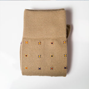 a pair of folded khaki geometric pattern dress socks on a white background
