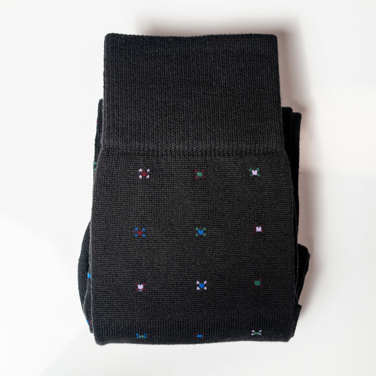 a pair of black geometric pattern dress socks folded on a white background