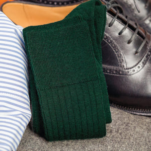 pair of Forest Green Merino Wool Over the Calf Dress Socks laying on top of nice clothing