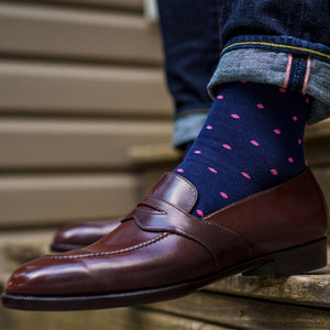 man sitting on stairs wearing dark brown loafers and navy cotton over the calf dress socks with pink dots pattern