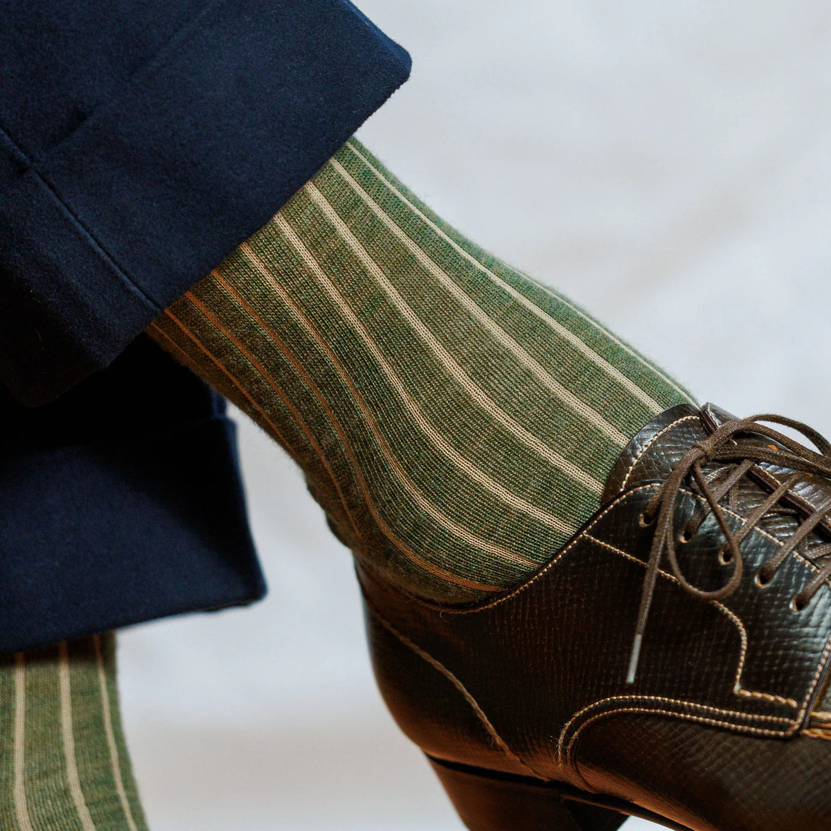 close up image of man wearing olive green striped mens wool dress socks and nice brown shoes