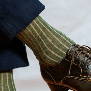 close up image of man wearing olive green striped mens wool dress socks and nice brown shoes