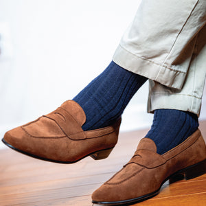 man crossing his legs wearing khaki slacks, brown loafers and over the calf length ribbed wool navy dress socks