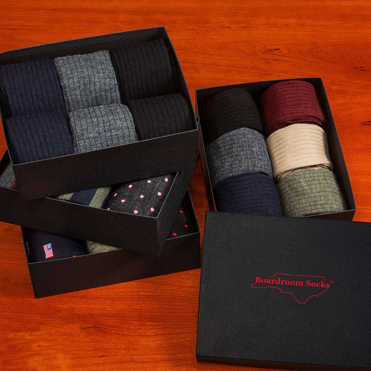 opened Boardroom Socks gift boxes filled with a variety of dress socks sitting atop wooden table