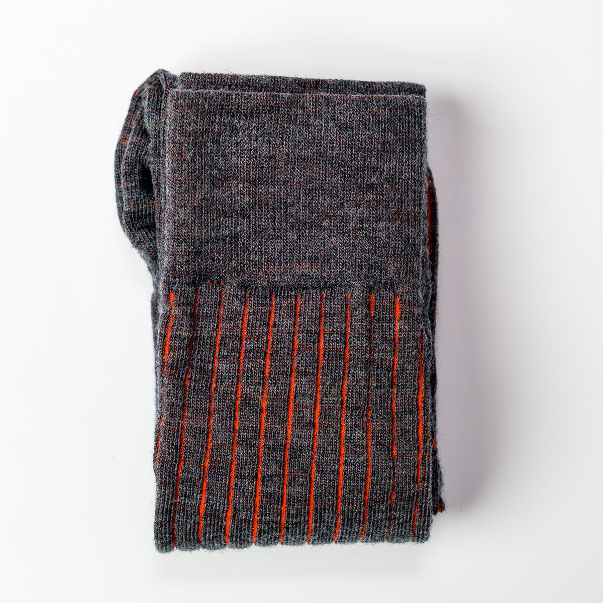 pair of grey and orange shadow stripe dress socks folded atop white table