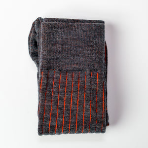 pair of grey and orange shadow stripe dress socks folded atop white table