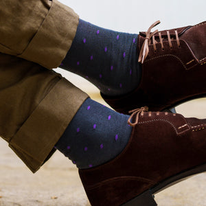 man wearing grey and purple patterned dress socks crossing ankles