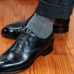 man wearing grey herringbone dress socks with a charcoal suit and black oxfords