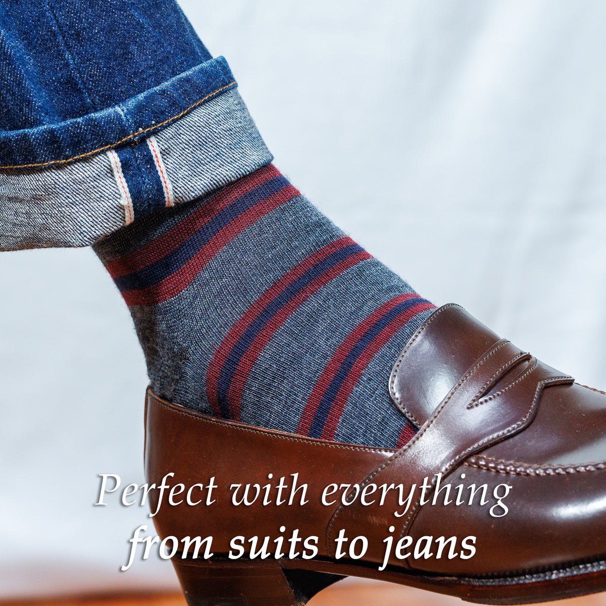 man wearing grey burgundy and navy striped dress socks with jeans and cordovan loafers