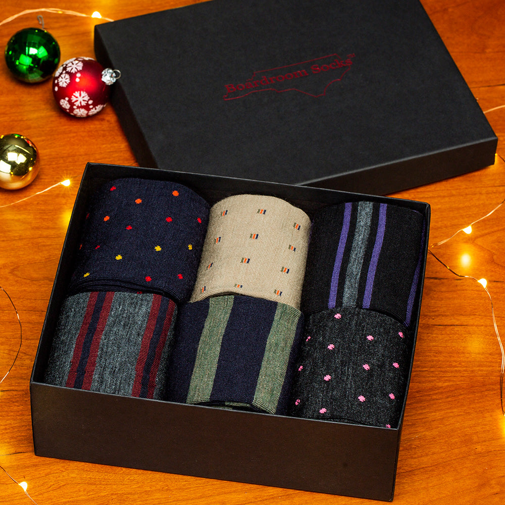 holiday decor surrounding gift box filled with patterned dress socks from Boardroom Socks