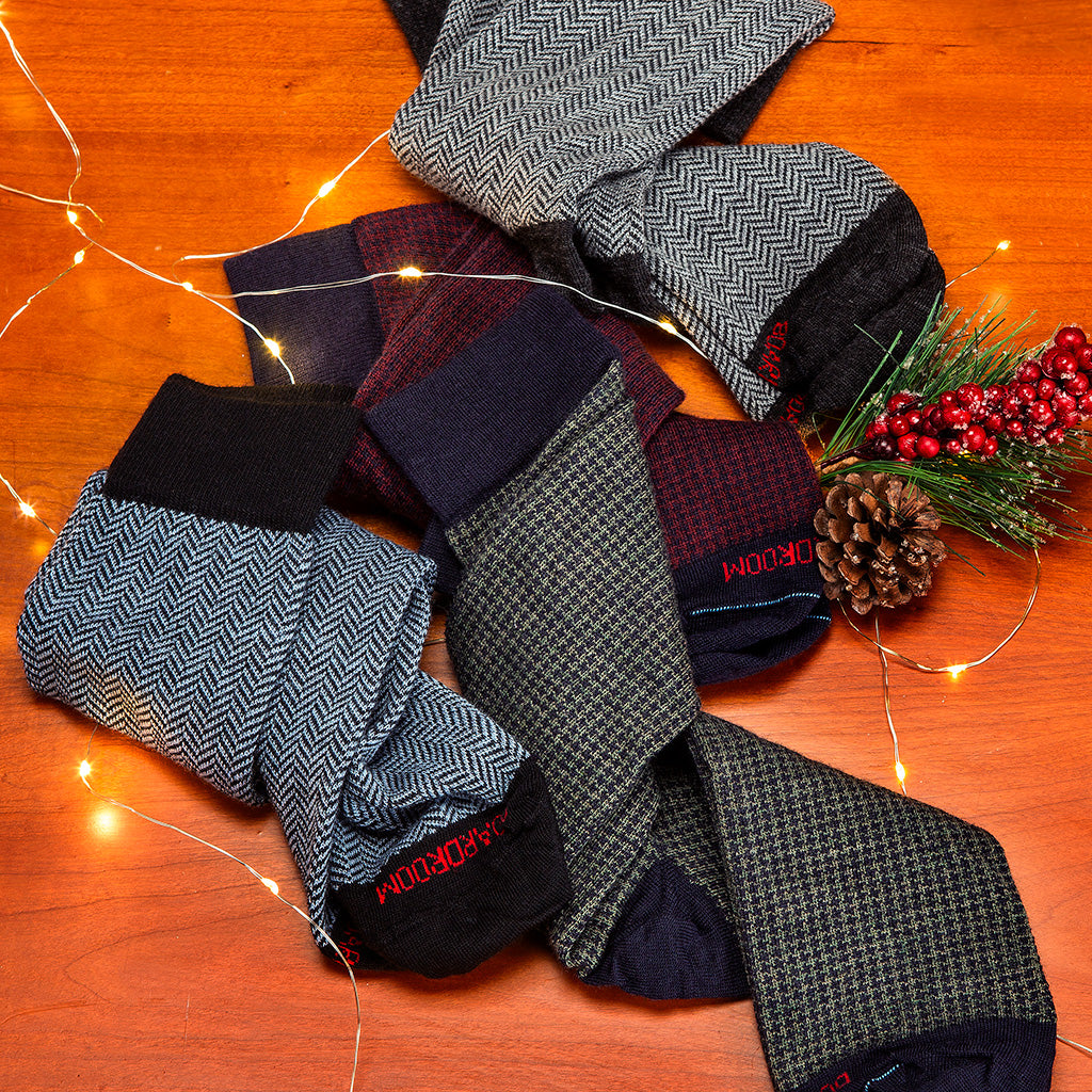 houndstooth and herringbone dress socks on a wood tabletop surrounded by holiday decor