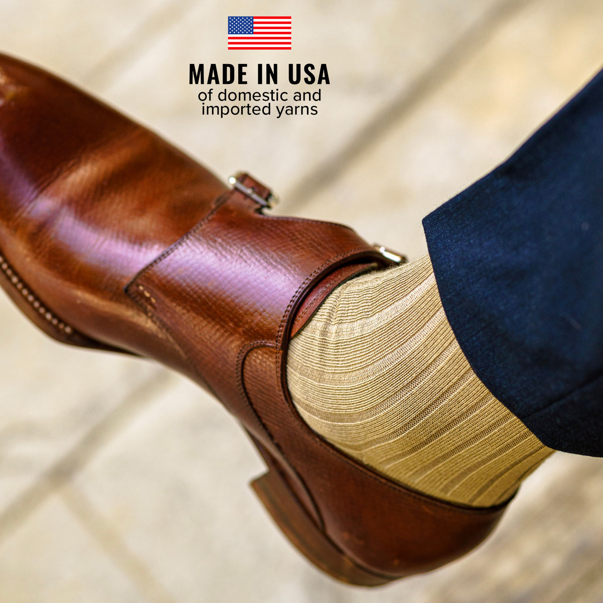 man crossing legs wearing khaki cotton dress socks with navy slacks and brown monkstraps