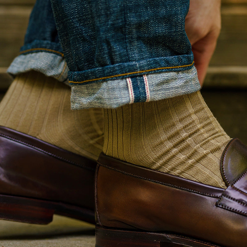 man walking wearing ribbed khaki dress socks with jeans and dark brown penny loafers