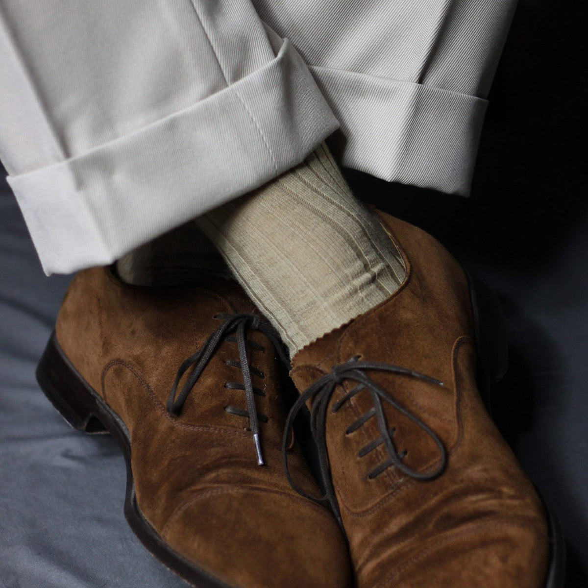 model with legs crossed wearing khaki merino wool dress socks and dress shoes