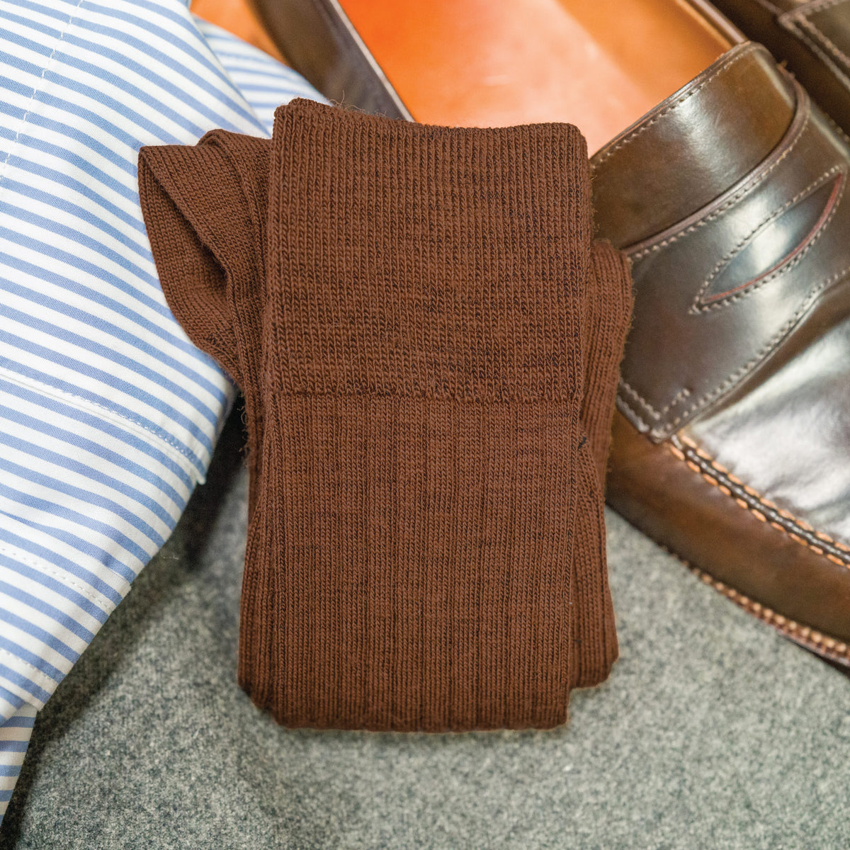 pair of Light Brown Merino Wool Mid Calf Dress Socks laying on top of nice clothing